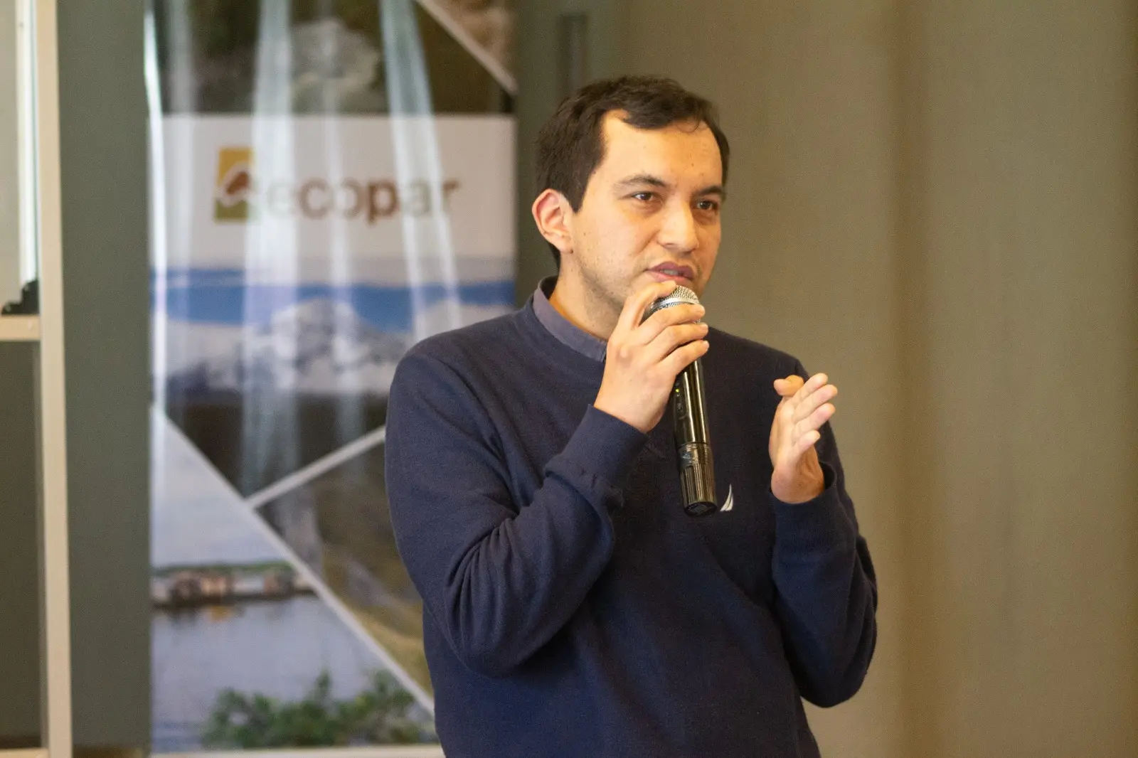 Ponente hablando por micrófono durante un evento de la organización ecopar enfocado en políticas ambientales.